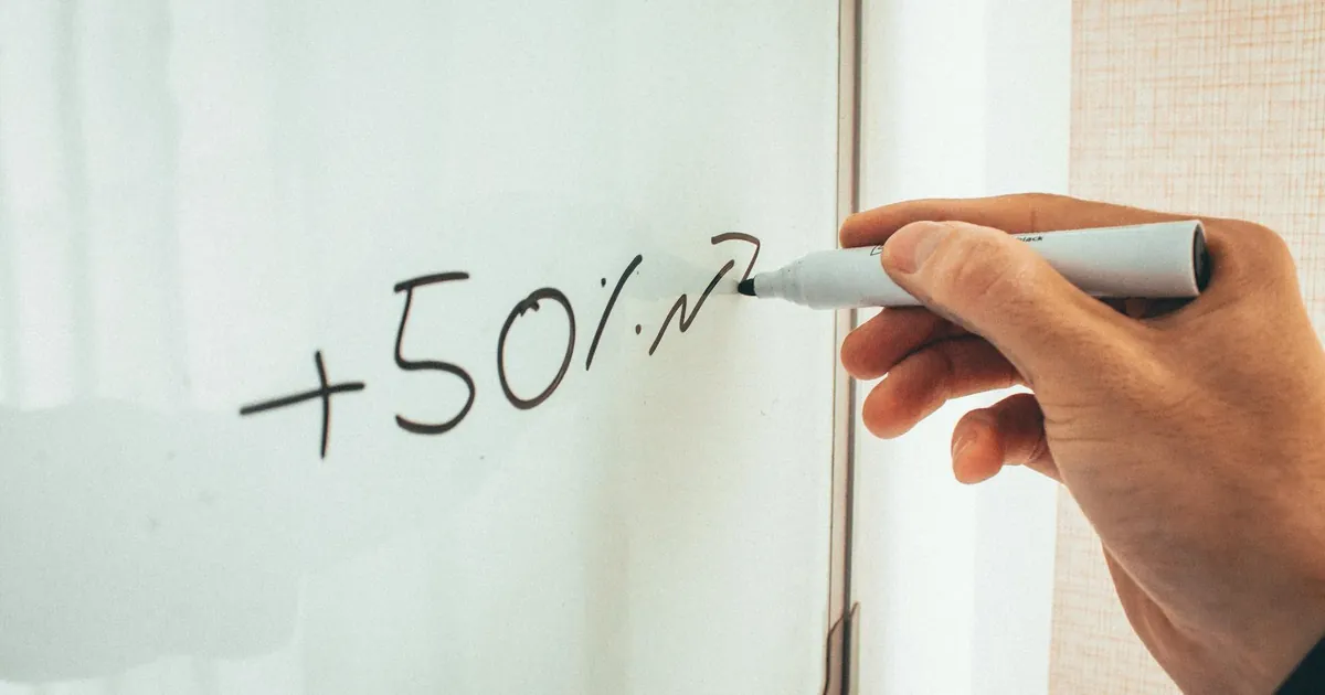 Crop anonymous male teacher writing math formulas on whiteboard during lessons in modern classroom