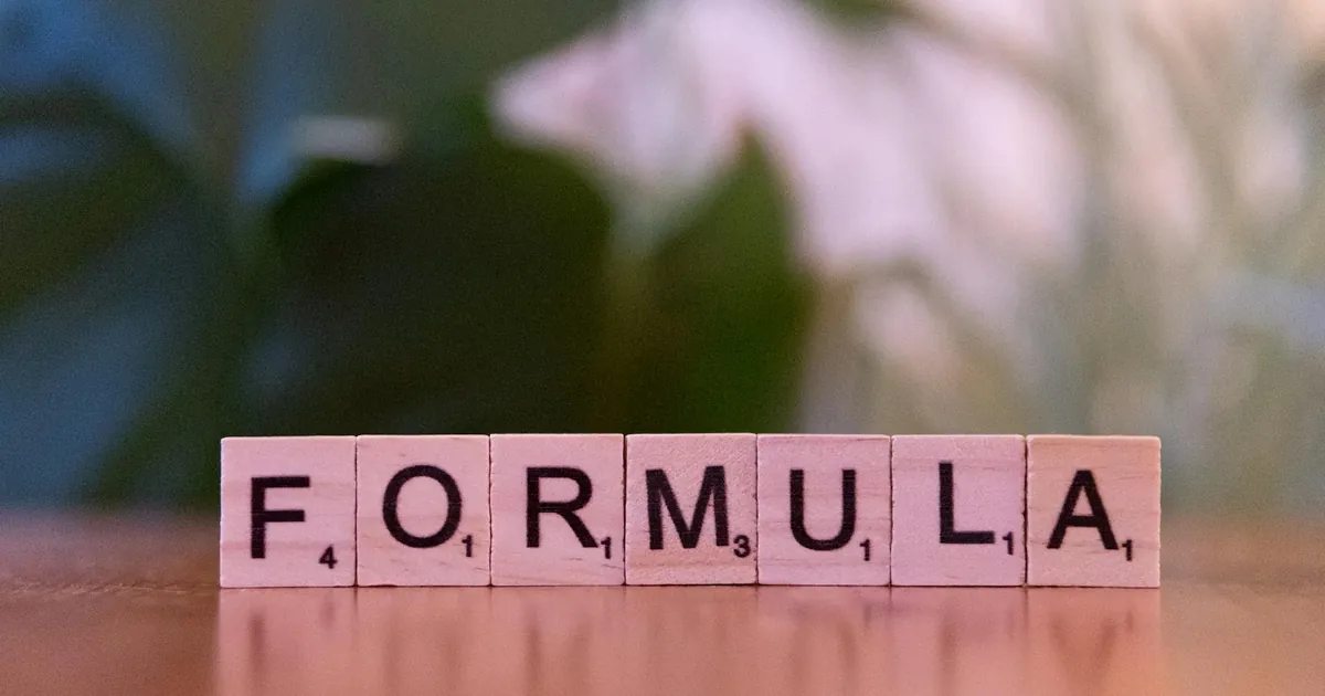 Close-up of Scrabble tiles spelling 'Formula' on a wooden surface with a blurred background. Close-up of Scrabble tiles spelling 'Formula' on a wooden surface with a blurred background.