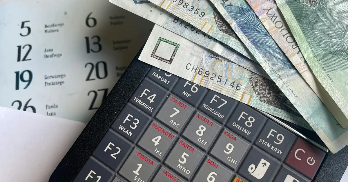 Close-up of Polish Zloty banknotes on a calculator with a calendar in the background.