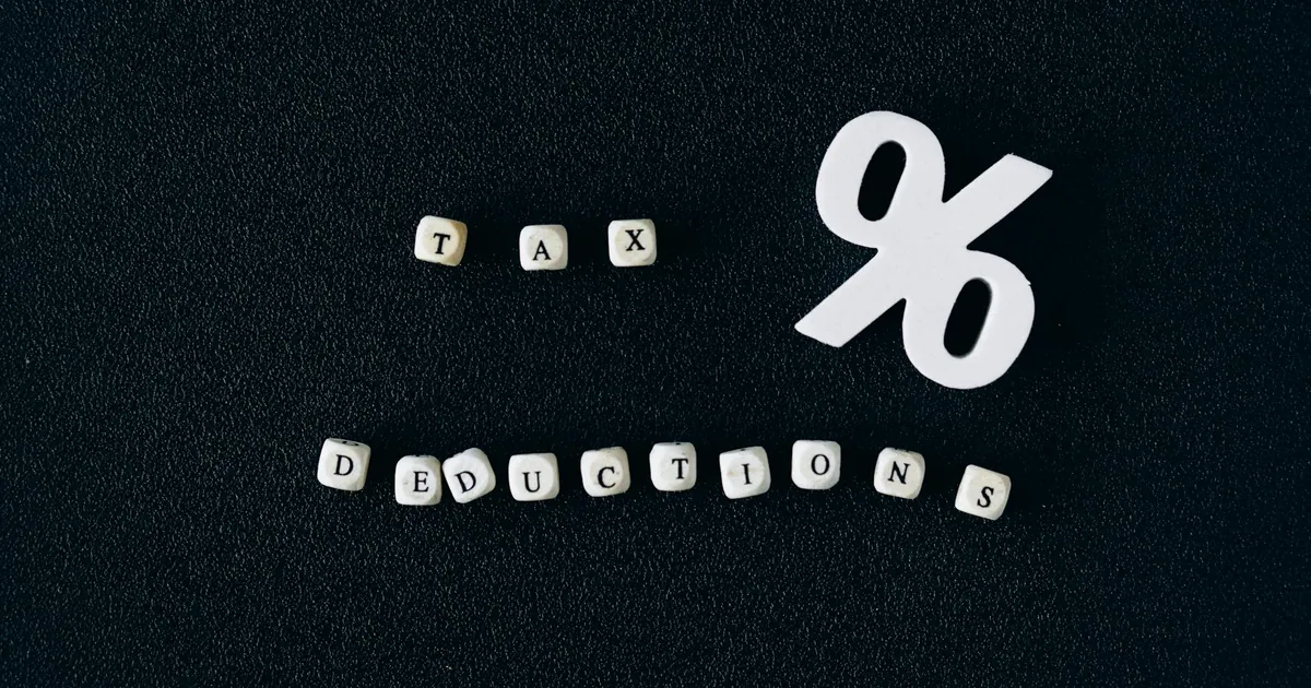 Conceptual image of tax deductions with alphabet blocks and percent symbol on black surface.