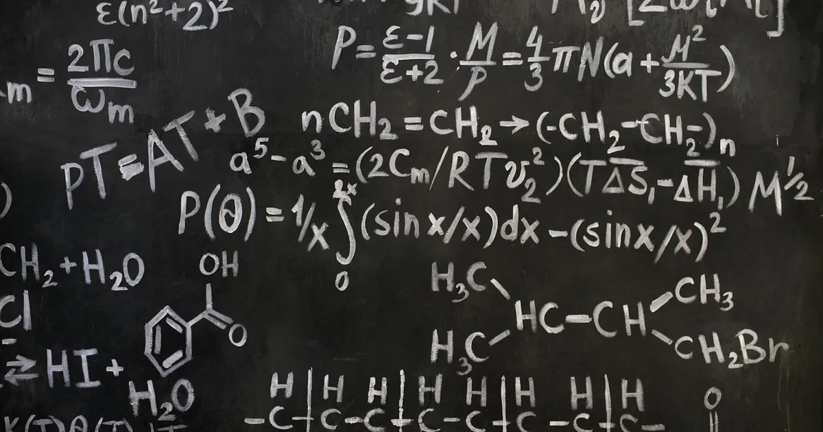 A close-up view of complex mathematical and chemical formulas on a blackboard.