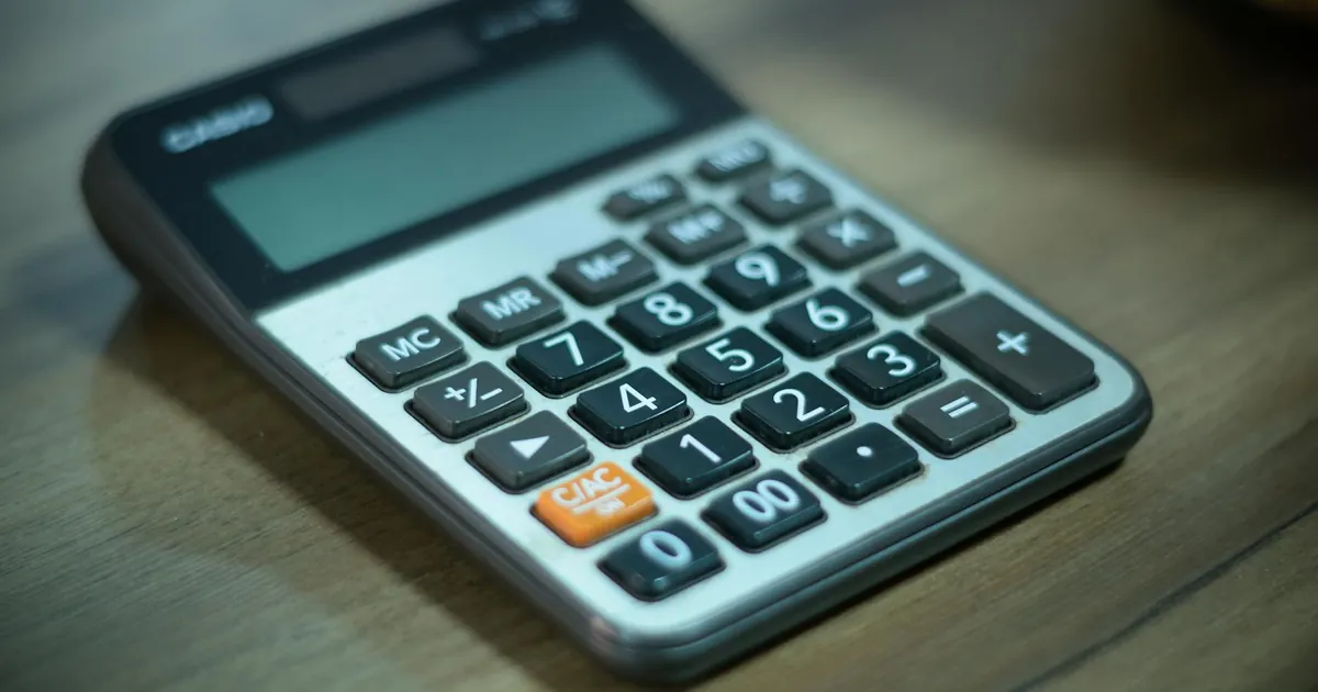 Digital calculator resting on a wooden table, selective focus.