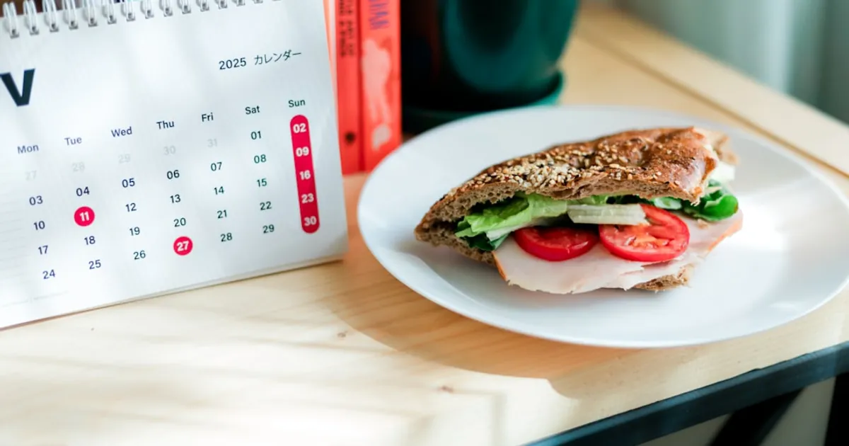 Sandwich with tomato and lettuce on a desk.