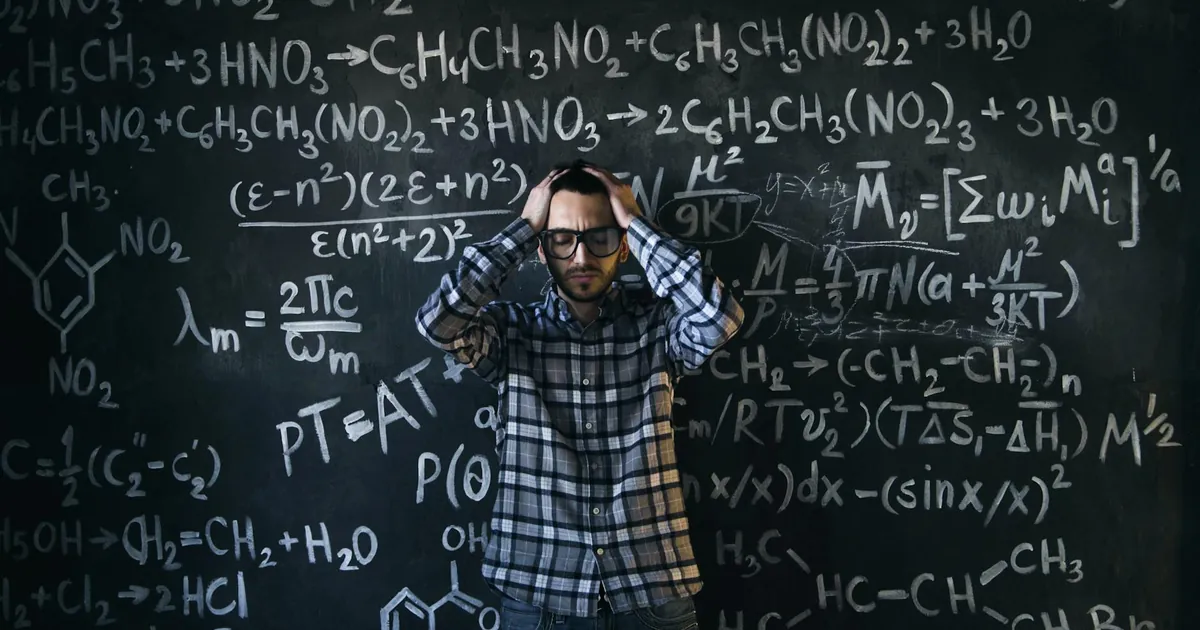 Man in glasses focusing on math problems, struggling with complex equations on chalkboard.