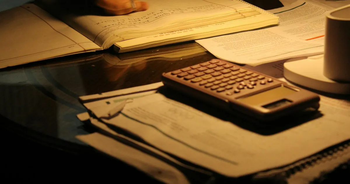 A focused study session at night with open books and a calculator on a dimly lit table.