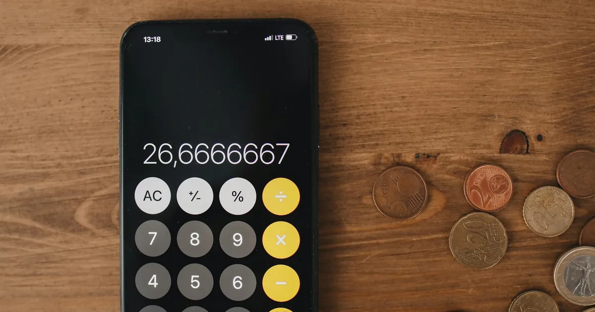 Close-up view of smartphone calculator and coins on wooden surface for financial metaphor.