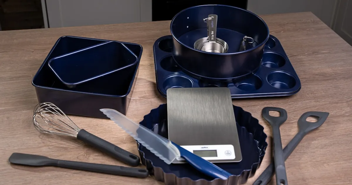 A wooden table topped with a pan, spatula and other kitchen utensils