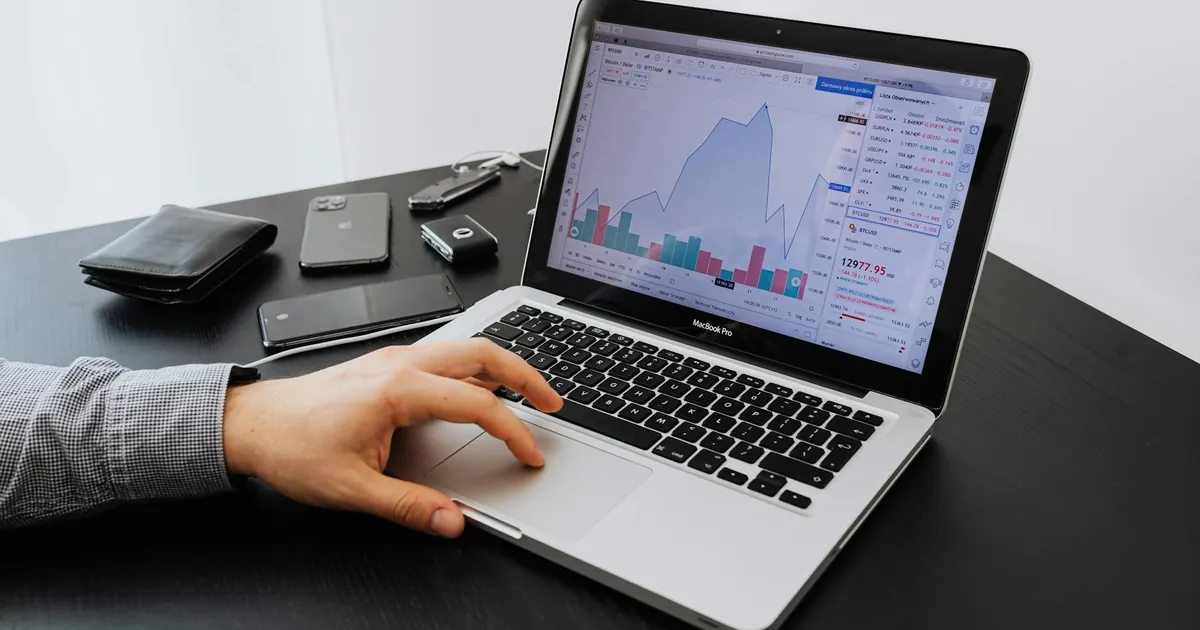 Person analyzing stock market data on a laptop at a desk.
