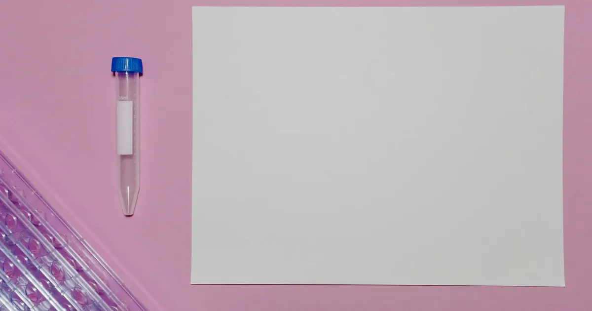Simple setup with a blank paper and test tube on a pink background for lab mockups. Simple setup with a blank paper and test tube on a pink background for lab mockups.