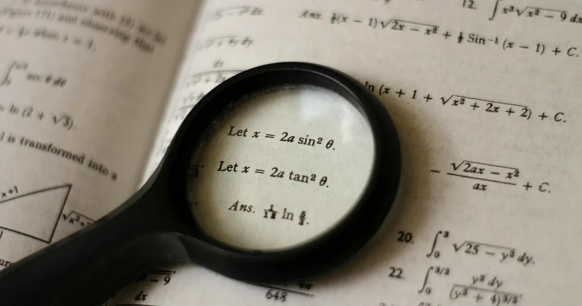 A magnifying glass focusing on mathematical equations in a textbook, symbolizing detailed study.