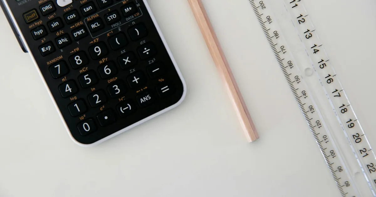Top view of a calculator, ruler, and pencil arranged on a white surface.