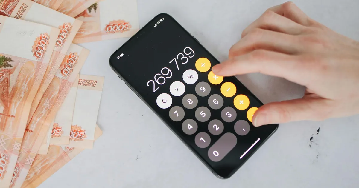 Person using smartphone calculator with Russian rubles on a table, representing financial planning.