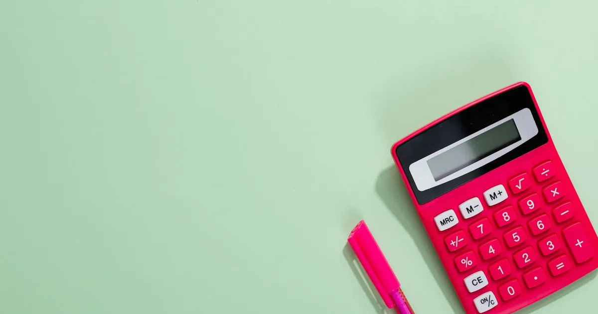 Pink calculator and pen on a pastel green background with copy space.