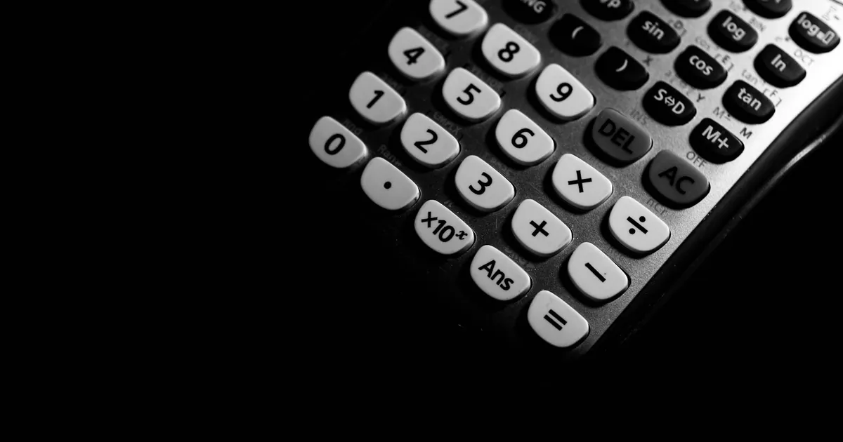 Detailed black and white photo of a calculator keypad highlighting numbers and functions.