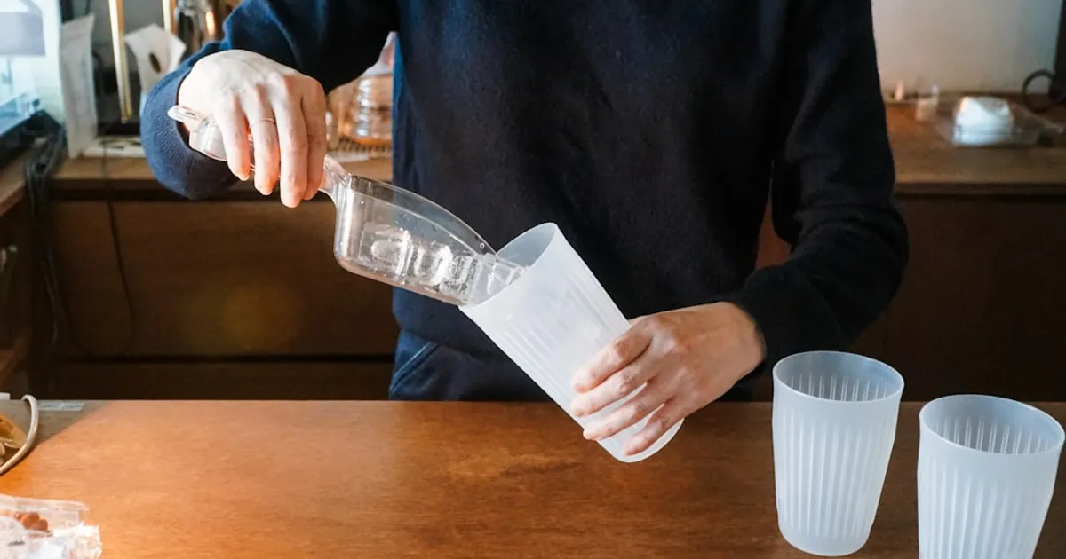 a man pours a drink into two plastic cups