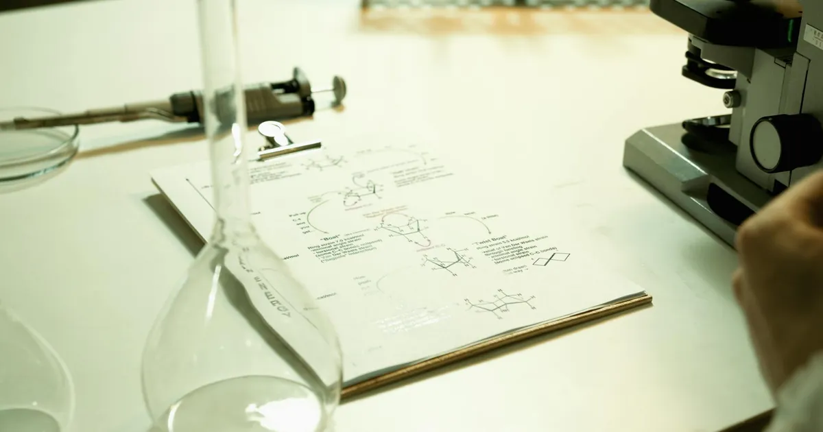 Close-up of a laboratory setup with documents, beaker, and microscope on a table.