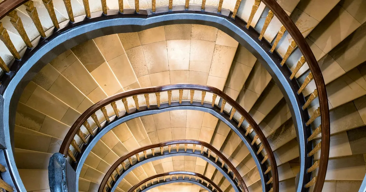 Intricate spiral staircase captured from above in a Hamburg building showcasing elegant curves. Intricate spiral staircase captured from above in a Hamburg building showcasing elegant curves.