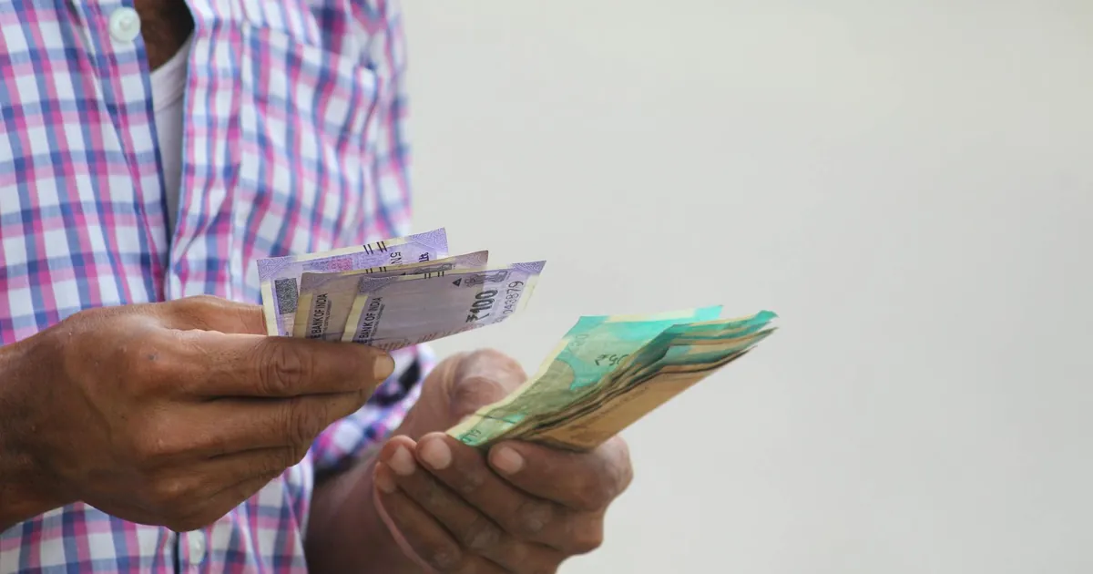 A person counts colorful banknotes, showcasing a financial transaction in detail.