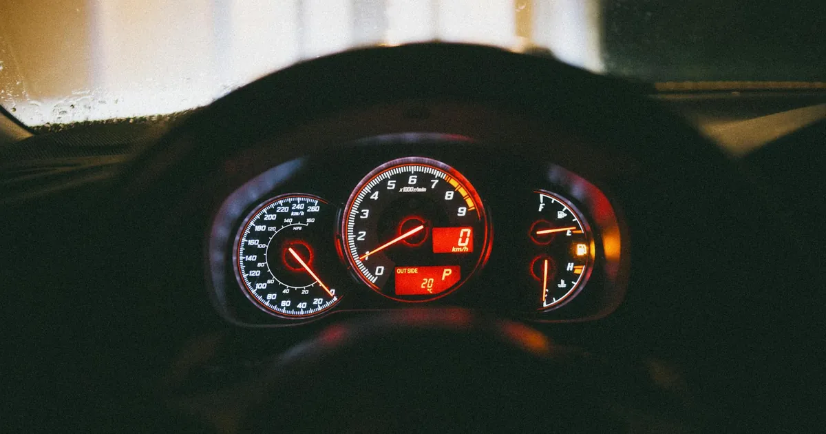 Close-up view of a car's dashboard with illuminated gauges and controls, captured at night.