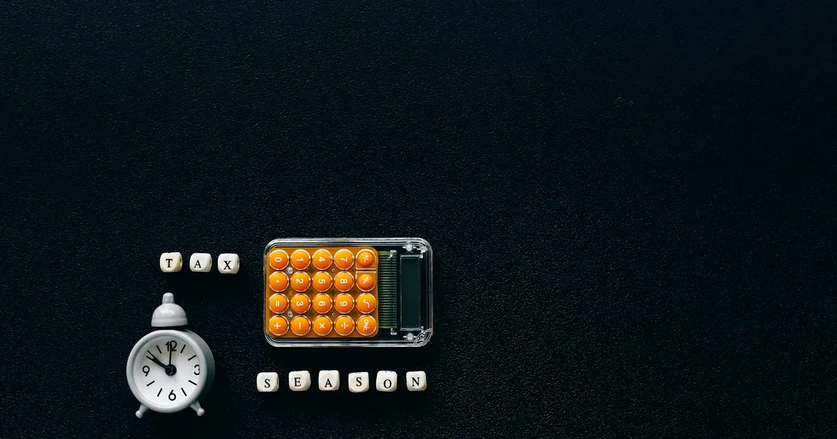 Flat lay of a tax season theme with a clock and calculator on a dark background. Flat lay of a tax season theme with a clock and calculator on a dark background.