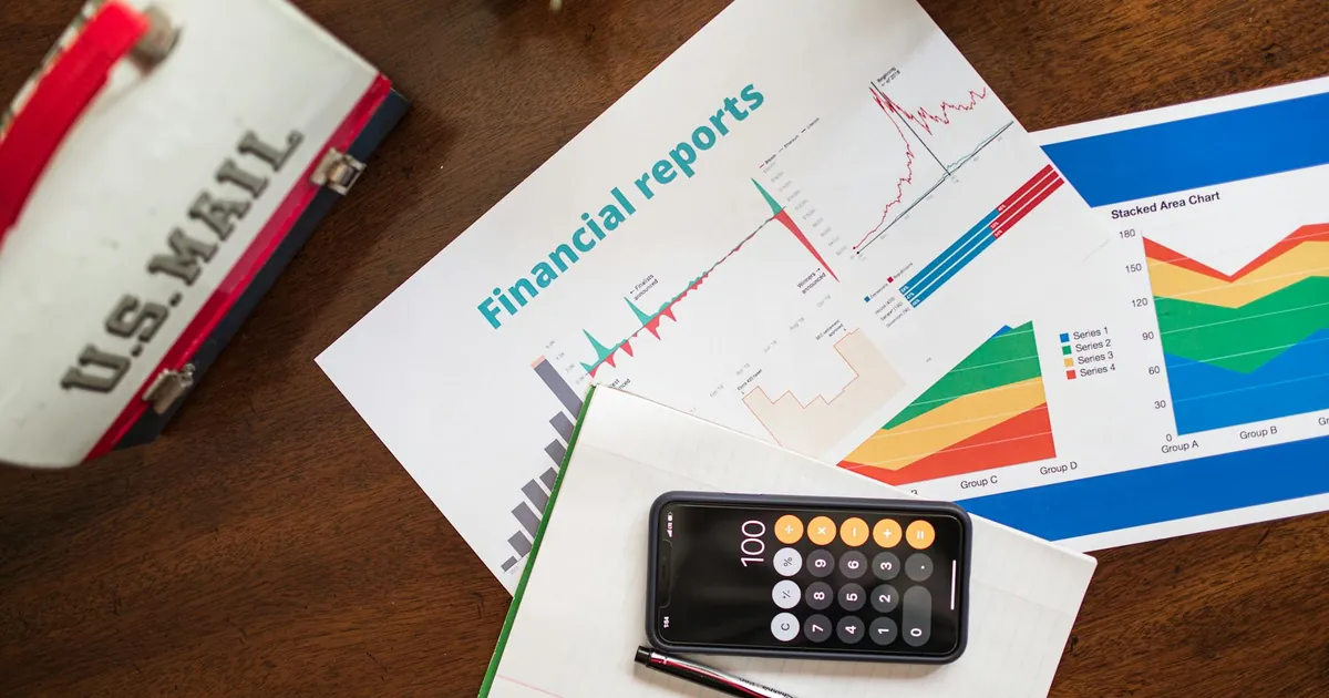 Overhead view of financial reports, charts, and a calculator on a desk.