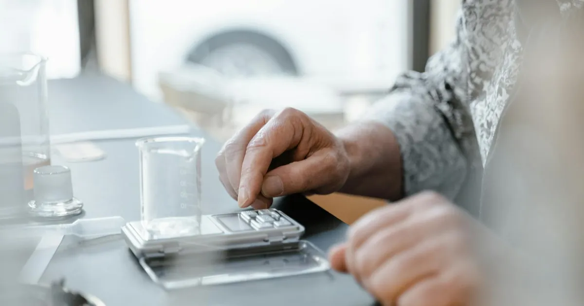 A hand uses a digital scale with a beaker in a laboratory setting. Perfect for scientific and educational content.